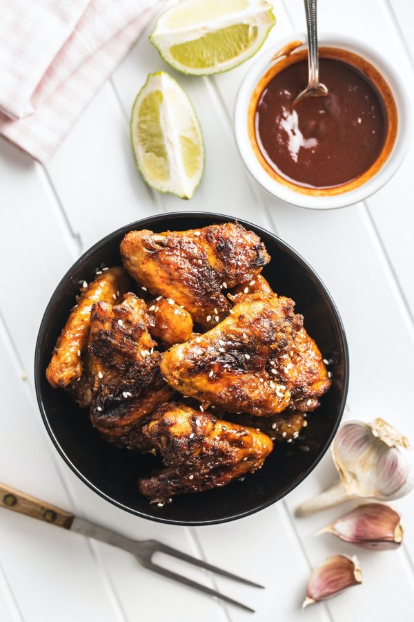 Grilled chicken wings in bowl with BBQ sauce.